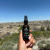 Girls hand holding a bottle of 'KAVEBROS Bedtime Spray' with a scenic background in Drumheller, AB